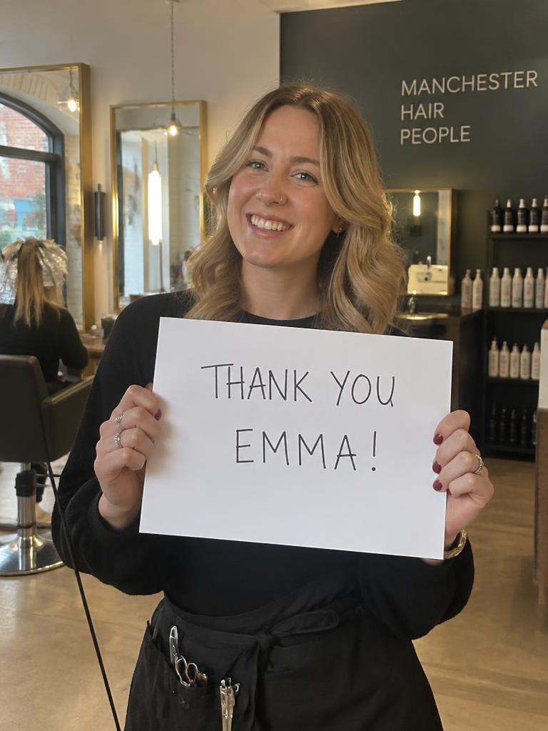 Team member holding a sign that says thanks Emma